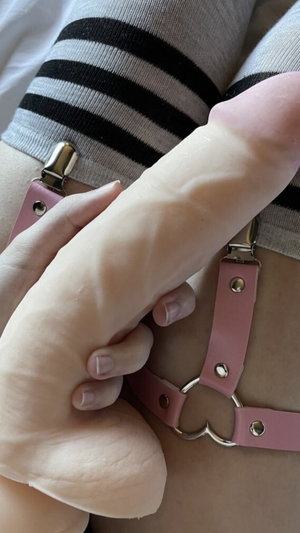 Person wearing striped socks and pink harness holding a flesh-colored object.