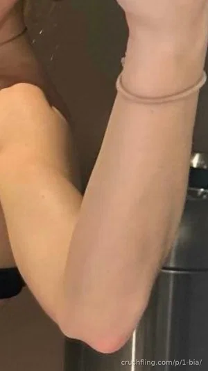 Close-up of arms and elbow, one wearing thin bracelet, partial black garment visible.