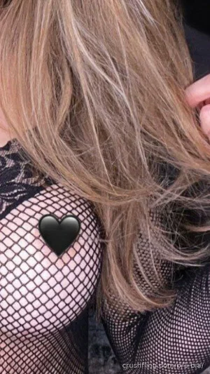 Woman with blonde hair wearing black fishnet top, showing shoulder and chest area.