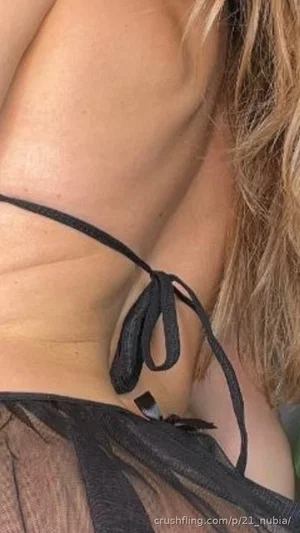 Woman with blonde hair wearing black lace top, close-up of shoulder and chest area.