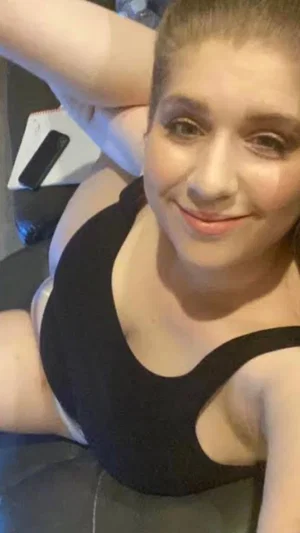 Woman with short hair in black top, smiling in indoor setting.
