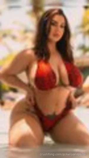 Woman in red bikini posing in shallow water at beach.