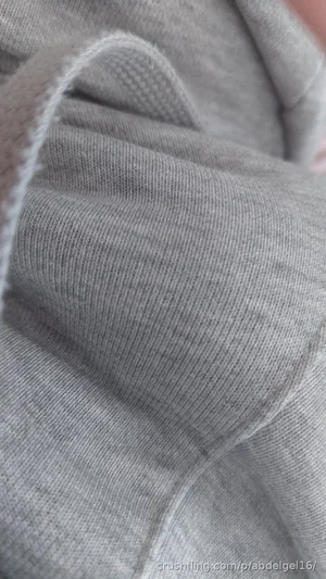 Close-up of gray fabric, possibly a sweater or hoodie, with visible stitching and texture.
