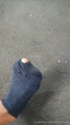 Foot in dark sock on pavement, no person visible.