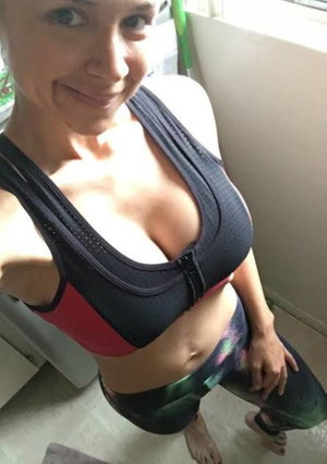 Woman in black and red sports bra and patterned leggings, posing indoors.