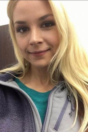 Blonde woman in fleece jacket taking indoor selfie.