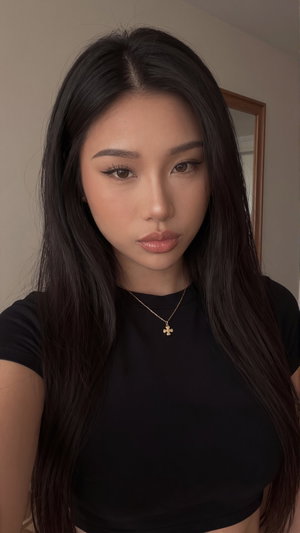 Woman with long black hair wearing black crop top, indoors, mirror in background.