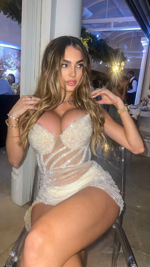 Woman in sparkly sheer dress posing indoors at event.