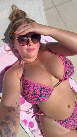 Curvy blonde in floral bikini taking outdoor selfie.