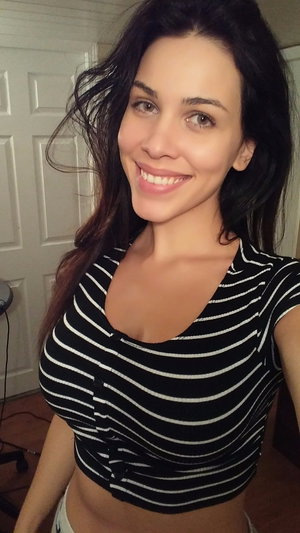 Brunette woman in striped crop top smiling indoors.