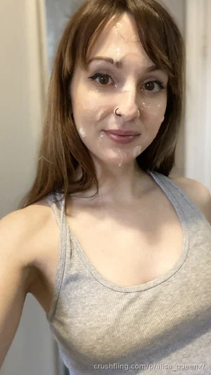Woman with brown hair and nose ring wearing gray tank top, face covered in clear liquid, indoor