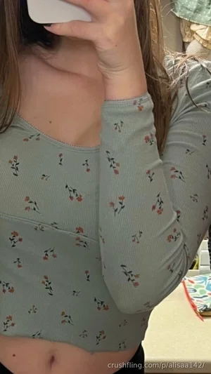Woman in floral long-sleeve top, holding phone, indoor setting.