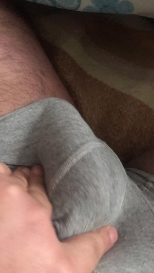 Person in gray shorts, hand on thigh, indoor setting.