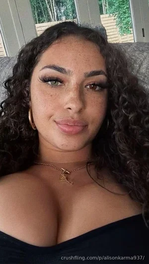 Woman with curly hair and freckles wearing black off-shoulder top, indoors.