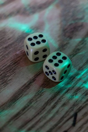 Two dice on wooden surface under green light.
