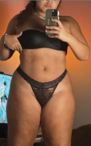 Woman in black lingerie taking mirror selfie indoors.