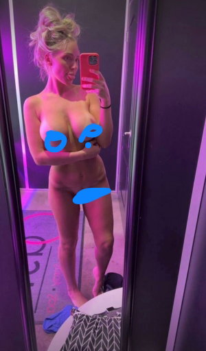 Blonde woman nude mirror selfie in bathroom.
