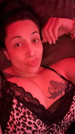 Woman with tattoos wearing leopard print lingerie lying down indoors.