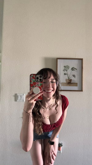 Woman with glasses in red top taking indoor selfie.