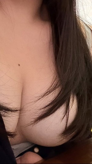 Woman with long dark hair in low-cut top showing cleavage.