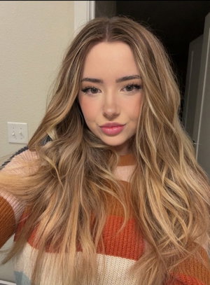 Woman with long wavy blonde hair wearing a striped sweater indoors.