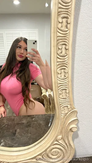 Woman in pink bodysuit taking mirror selfie in indoor setting.