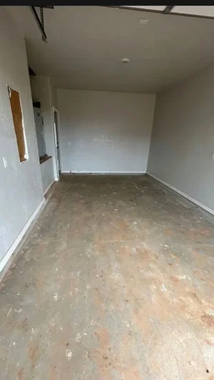 Empty garage with concrete floor and white walls, no people visible.