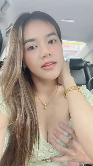 Asian woman with long hair in green top inside car.