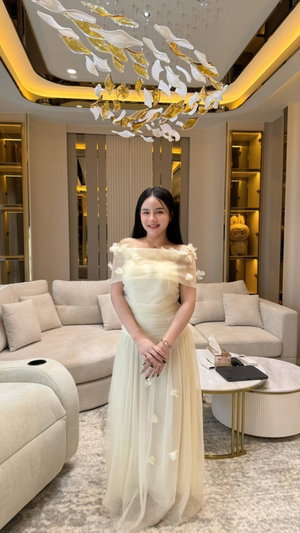 Woman in cream dress standing in modern living room.