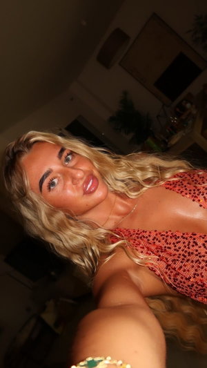 Blonde woman in red top taking indoor selfie.