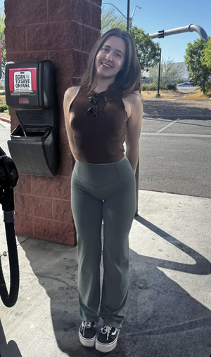 Woman in brown top and green pants at gas station.