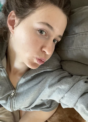 Woman in grey hoodie taking indoor selfie.