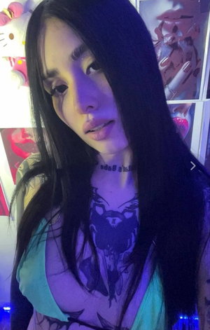 Asian woman with long black hair and tattoos in sheer top.