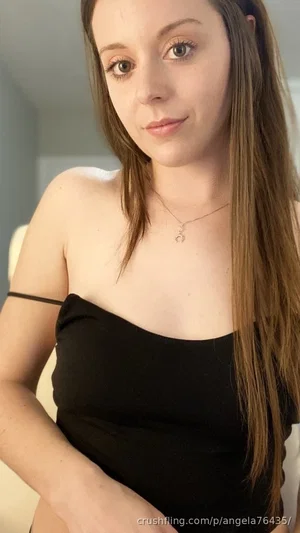 Woman with long brown hair in black strapless top, indoors, looking at camera.