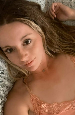 Woman with blonde hair in lace lingerie on bed.