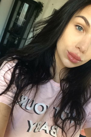 Woman with black hair in pink t-shirt indoors.