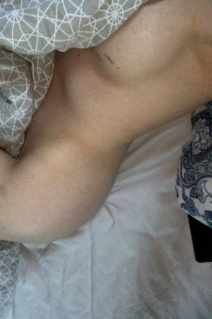 Person reclining on bed with patterned sheets.