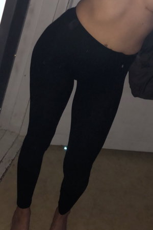 Fit woman in black leggings standing indoors.