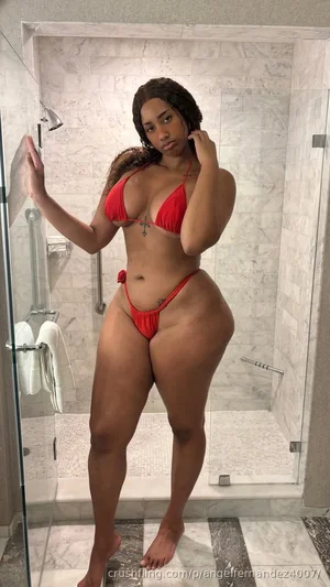 Woman in red bikini posing in marble shower, curvy body, indoor setting.