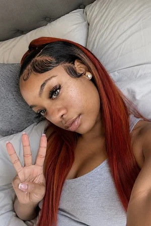 Woman with red hair in gray tank top on bed.
