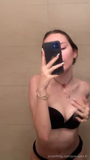 Woman in black lingerie posing in bathroom mirror selfie.