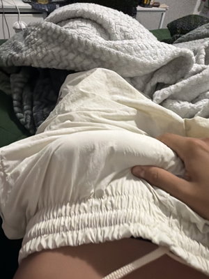Person in white shorts lying on bed with blankets.