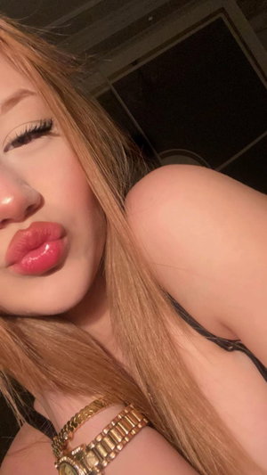 Woman with long blonde hair in black top taking selfie indoors
