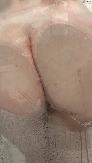 Close-up of bare buttocks with soap suds, in a shower setting.
