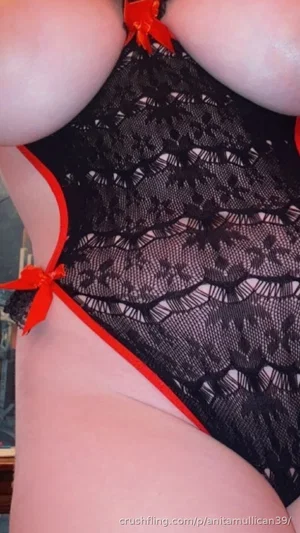 Woman in black lace lingerie with red trim, close-up of torso and hips.