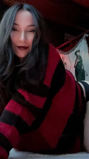 Woman with gray hair wearing red and black striped sweater, lying indoors.