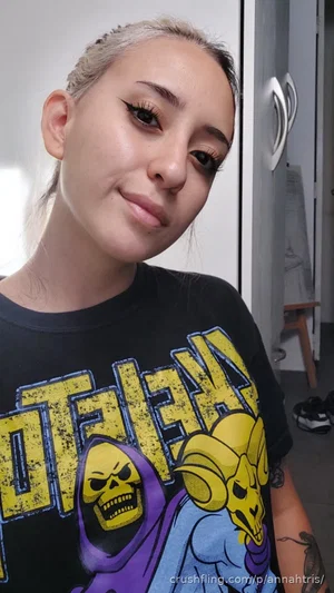 Woman with silver hair and graphic tee, indoor selfie, tattoos visible.
