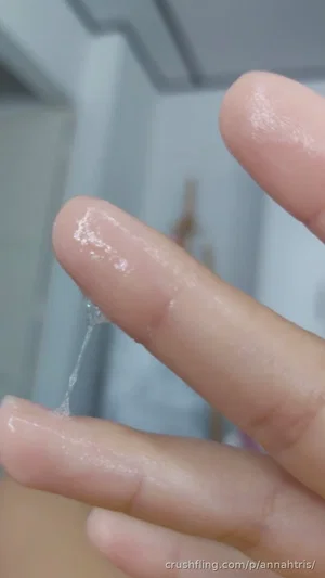 Close-up of fingers with clear viscous liquid, likely in a bathroom setting.