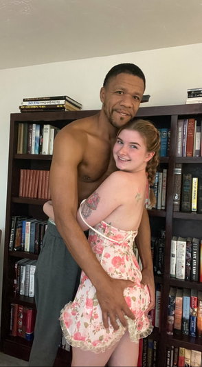 Couple posing together in front of bookshelf.