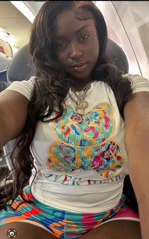 Woman with long dark hair in colorful outfit sitting in airplane seat.
